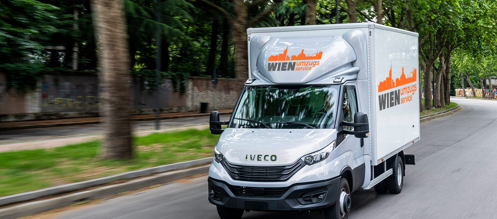 Ein Transporter der Marke 'Iveco' mit der Aufschrift 'Wien umzugsservice' fährt die Straße entlang