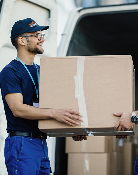 Zwei Arbeiter halten eine große Kiste in den Händen und bringen sie in den Transporter