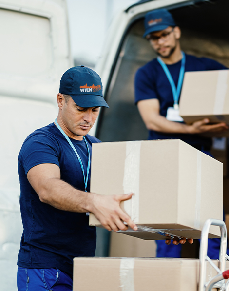 Zwei Arbeiter eines Umzugsunternehmens holen Kisten aus einem LKW